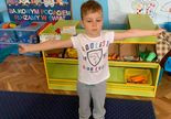 Terapia ręki w grupie 1. Chłopiec stoi z wyciągniętymi w bok rękami.